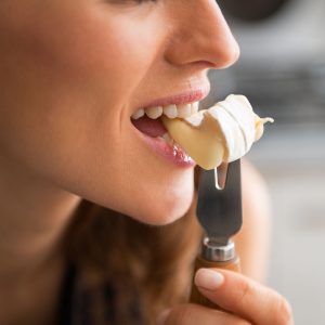 Closeup on young woman eating camembert